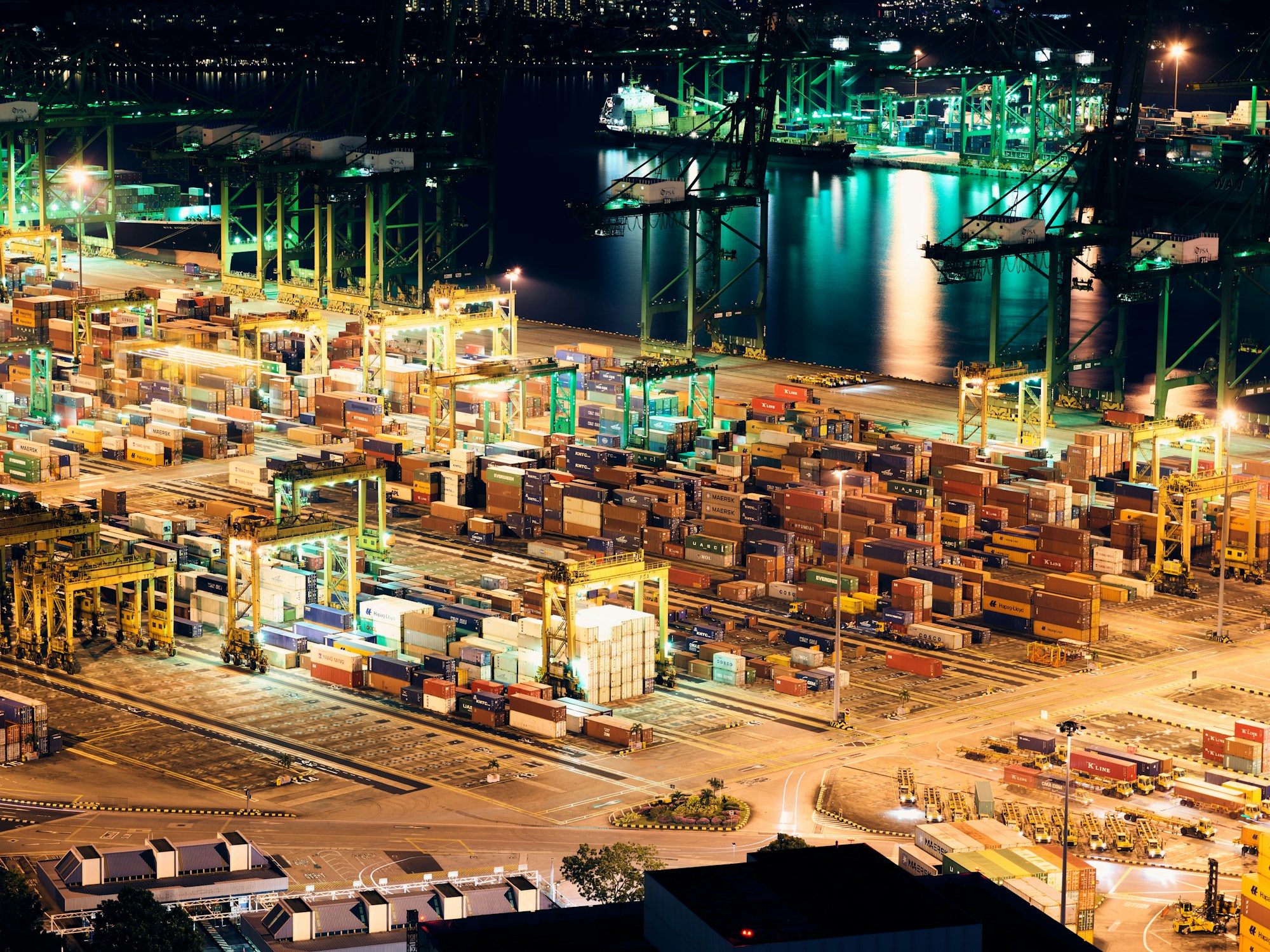 A container terminal illuminated beside a harbour at night